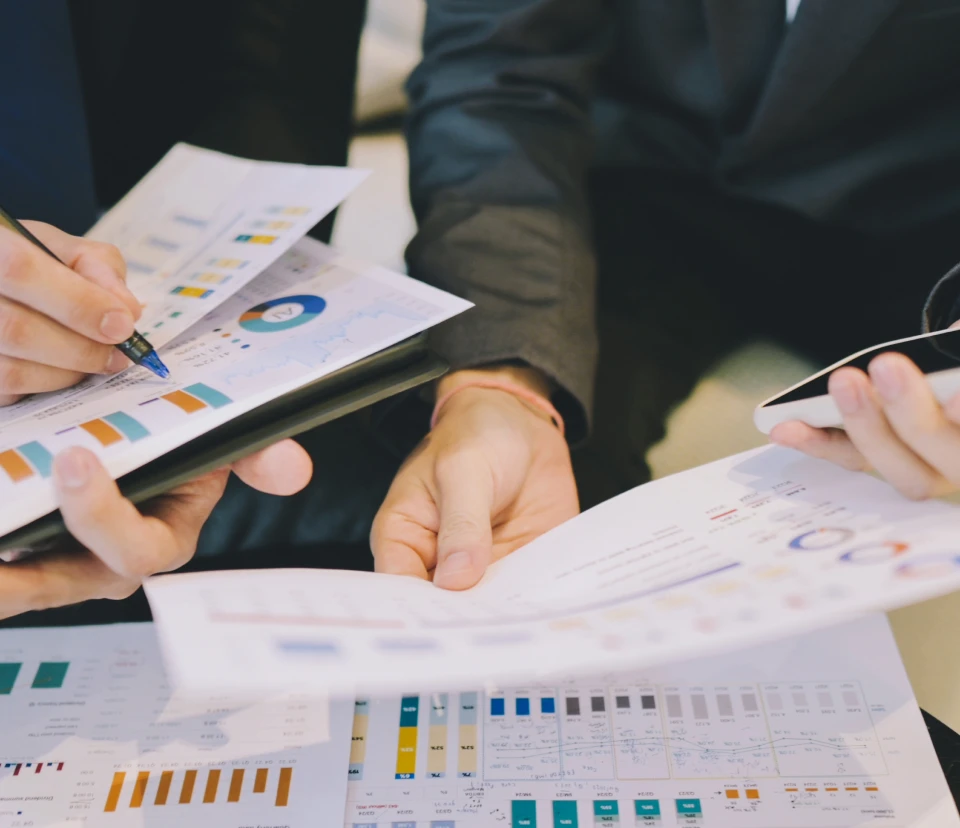 Hands discussing financial reports and graphs